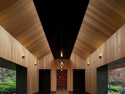 A minimalist restaurant interior with wooden walls and a long wooden table.
