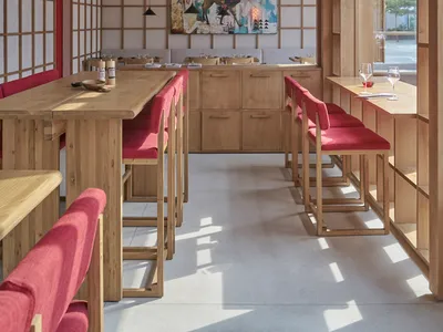 Modern restaurant interior with wooden furniture and vibrant artwork.