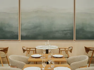 簡約風格的餐廳室內，擺放木質餐桌、餐椅，並飾有抽象牆面藝術。
