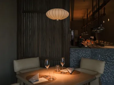 Modern dining room with stone walls, wood furniture, and metal accents.