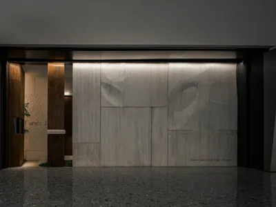 Modern entrance to a restaurant featuring marble walls and a wooden door.
