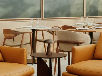 Modern restaurant lounge with contemporary furniture, leather upholstered seats, wooden tables, and glass accents.