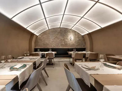 A modern restaurant interior with marble walls, wooden tables, and metal accents