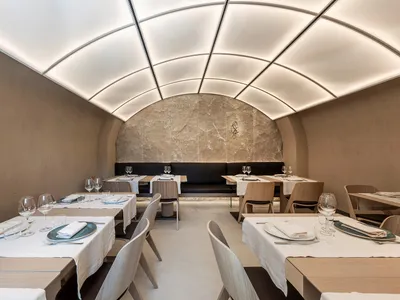 A minimalist restaurant interior with clean line furniture and a curved ceiling.