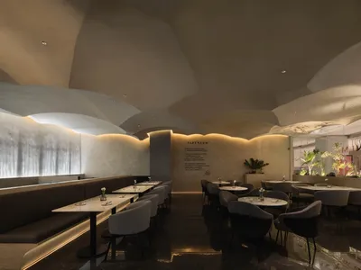 Interior of a modern restaurant featuring concrete walls, marble surfaces, and ambient lighting.