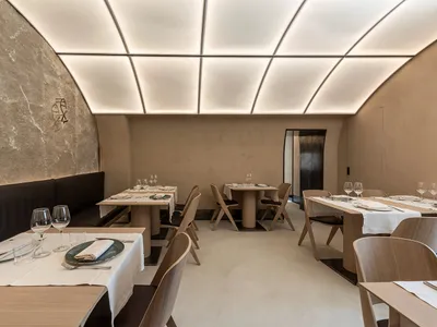 Modern restaurant interior with minimalist design featuring neutral-toned decor and lighting.