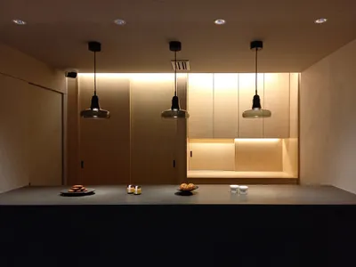 A modern kitchen with wooden cabinets and pendant lights hanging from the ceiling.