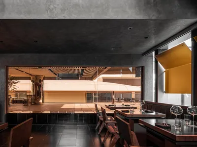 Modern restaurant interior with concrete walls and wooden tables
