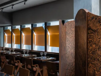 A modern restaurant interior featuring wooden furniture and a dark, contemporary design.