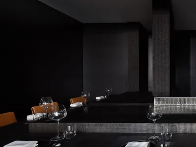A minimalist restaurant interior showcasing sleek black marble finishes and contemporary seating arrangements.