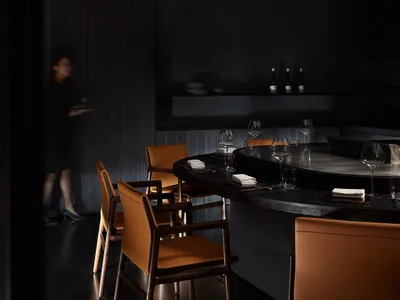 A stylish modern restaurant interior with dark wood and leather accents.