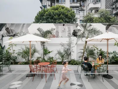 Outdoor seating area of a cafe with metal tables, glass umbrellas, and concrete walls