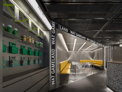 Modern restaurant interior featuring black metal and glass elements, yellow seating areas, and illuminated signage.