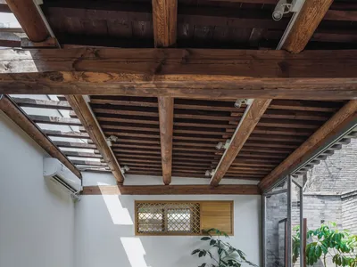 A cozy cafe interior featuring wooden furniture, including tables, chairs, and stools.