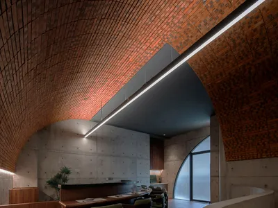 A modern restaurant dining room with concrete and brick walls and a circular arch.