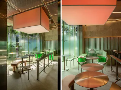 Modern restaurant interior with metal tables and chairs, glass walls, and green accents.
