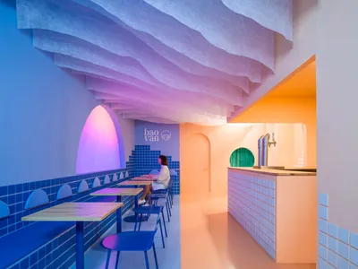 Modern, minimalist restaurant interior with bright colored tiles and wave-shaped ceiling.