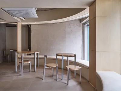 A modern cafe interior featuring wooden furniture, concrete walls, and metallic accents.