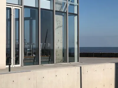 Modern restaurant interior with glass and concrete elements.