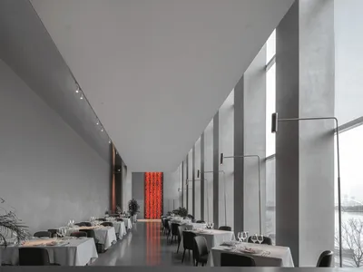 Modern restaurant with concrete walls, glass columns, and white tables and chairs.