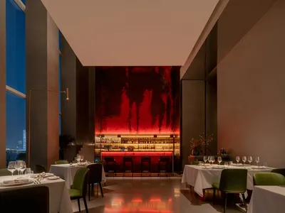 現代工業風餐廳室內，搭配紅色燈光與綠色座椅。