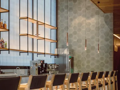 Modern restaurant interior with wooden bar counter and black leather stools