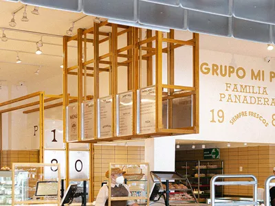 麵包店室內空間，木製櫃檯展示烘焙商品，員工戴著口罩。
