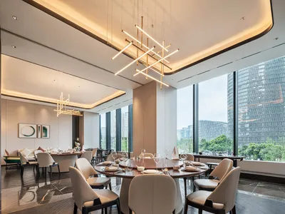 A modern minimalist dining room featuring luxury materials with a large round table and white chairs.