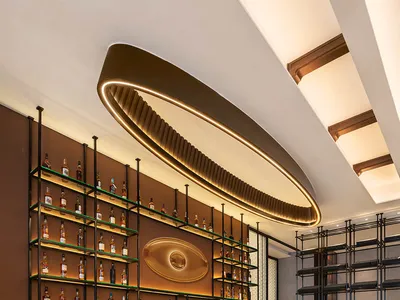 Modern bar interior with marble countertop and metal accents, illuminated by circular lighting fixture.