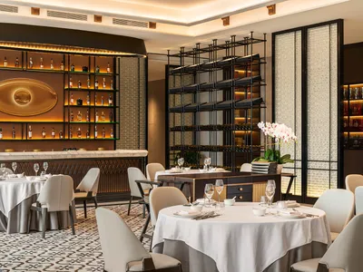 A modern fine dining restaurant with elegant interiors, white tablecloths, and wine racks.
