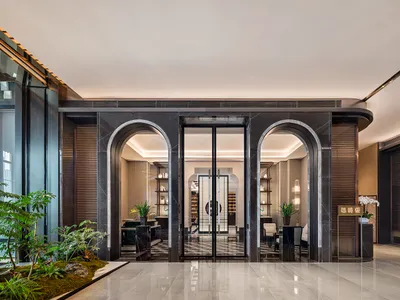 Modern hotel lobby with marble archways and glass doors.