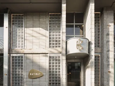 Concrete and glass exterior of a modern restaurant with a logo that reads "KATINAT"