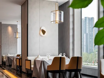 Modern restaurant interior with contemporary design elements and large windows overlooking urban landscape.