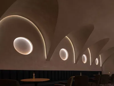 Modern minimalist restaurant interior with circular cutouts in the concrete ceiling.