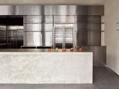 View of a modern cafe interior with a concrete shelf displaying pastries.