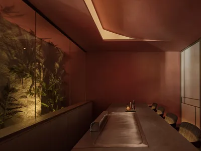 A minimalist restaurant interior featuring a brick counter and seating area.