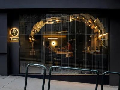 A modern restaurant entrance featuring glass walls and lighting fixtures.