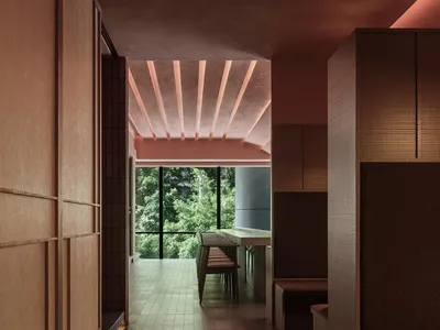 A modern restaurant interior featuring a long wooden counter and seating area surrounded by lush greenery.