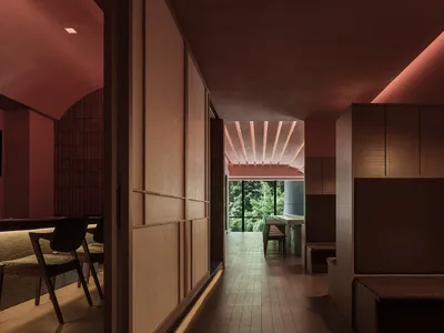 A modern restaurant interior featuring wooden walls, a red ceiling with embedded lighting, and a view of greenery through lar