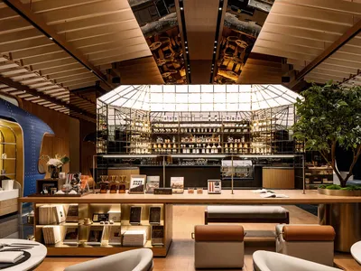 A well-lit, modern coffee shop with wooden accents, showcasing a variety of coffee-related items and a large glass window.