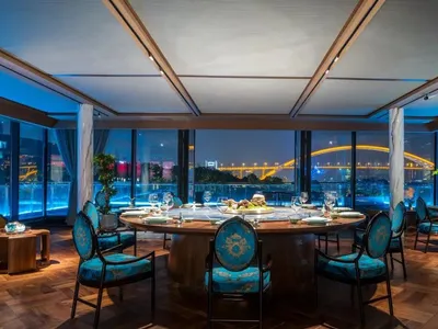 A modern restaurant with glass walls and a view of a bridge at night