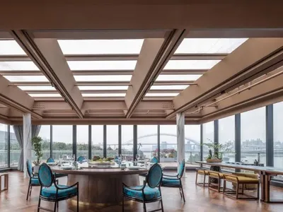 Contemporary restaurant interior featuring modern furniture, wooden floors, glass windows, and metal accents.
