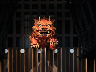 A modern bar interior with wooden accents, featuring a large red mascot statue.