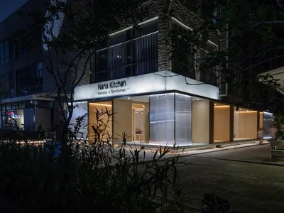 Modern restaurant exterior at night with illuminated signage and seating area.