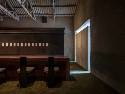 現代簡約餐廳室內，搭配深色木質座椅與混凝土牆面。