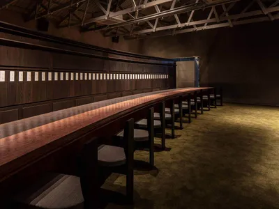 Long wooden restaurant counter with chairs and menu cards attached to the wall.
