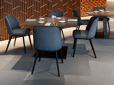 A modern restaurant interior featuring a table setting with gray fabric chairs and a wooden lattice wall.