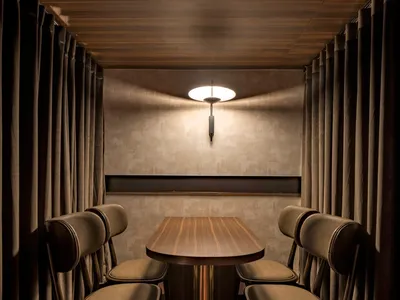 Modern restaurant cubicle with wood table and fabric-covered chairs.