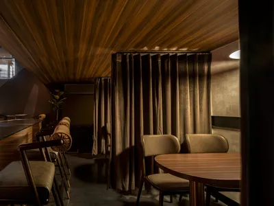 A modern-themed restaurant bar interior with wooden furniture and paneling.