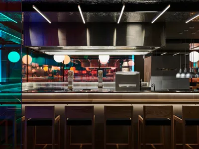 A modern restaurant bar with metallic cladding and colorful lighting.